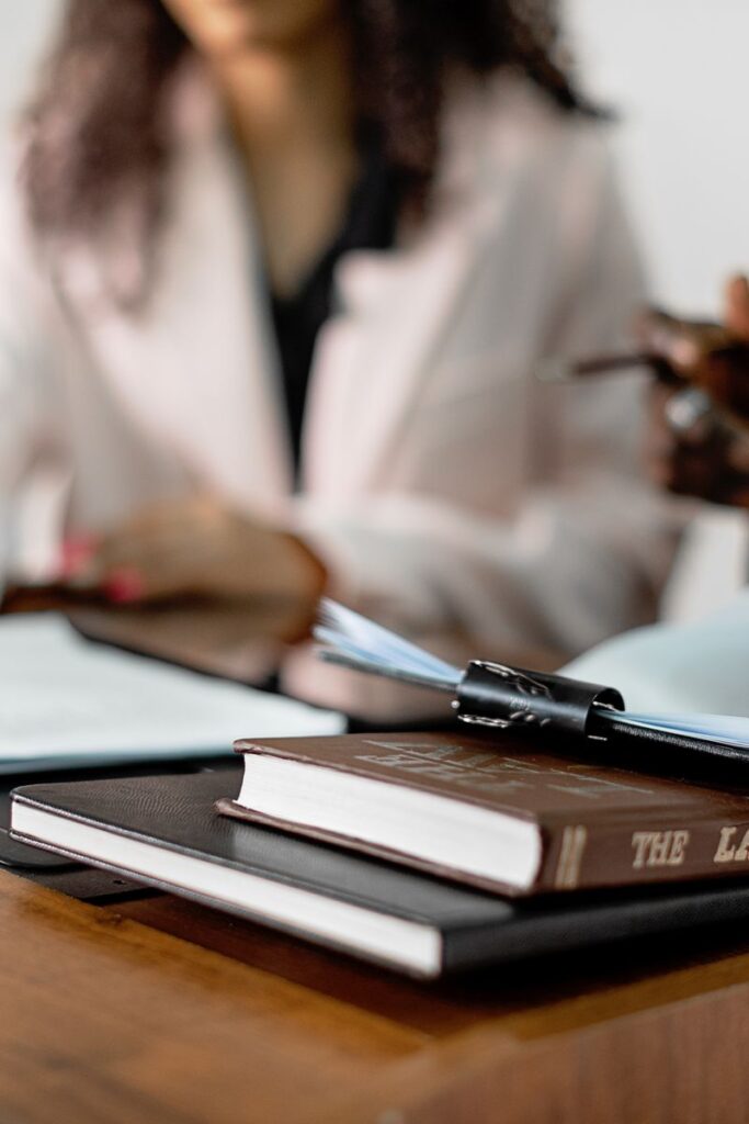 Two lawyers reviewing documents with law books on a desk. Professional legal environment.